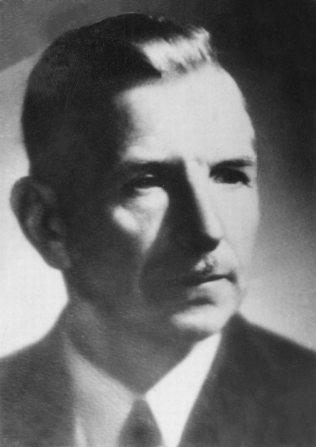 Antonin Plichta, black and white studio portrait of a middle-aged man with swept back hair, in a suit and tie