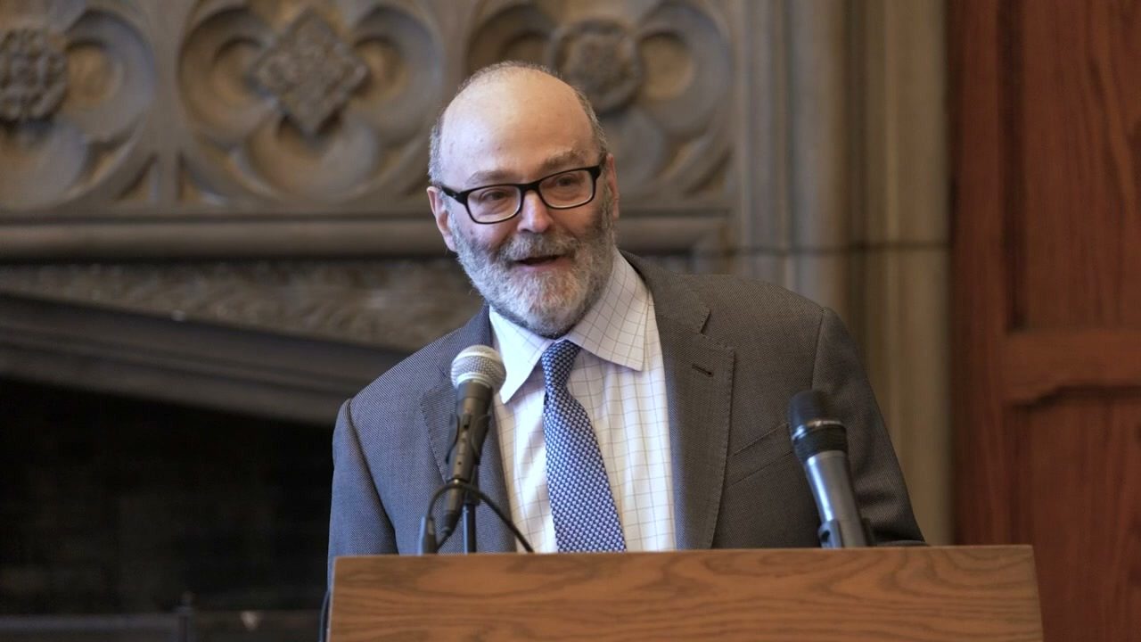 Bruce Lincoln speaking at a podium in the University of Chicago Divinity School