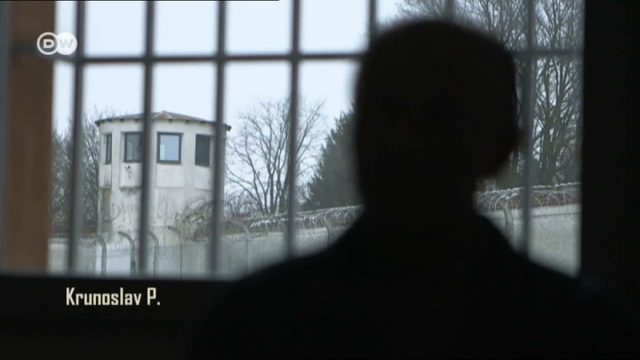 A man in silhouette at a barred prison window looking out at a watchtower and a razor wire wall, the caption Krunoslav P. in the lower left corner