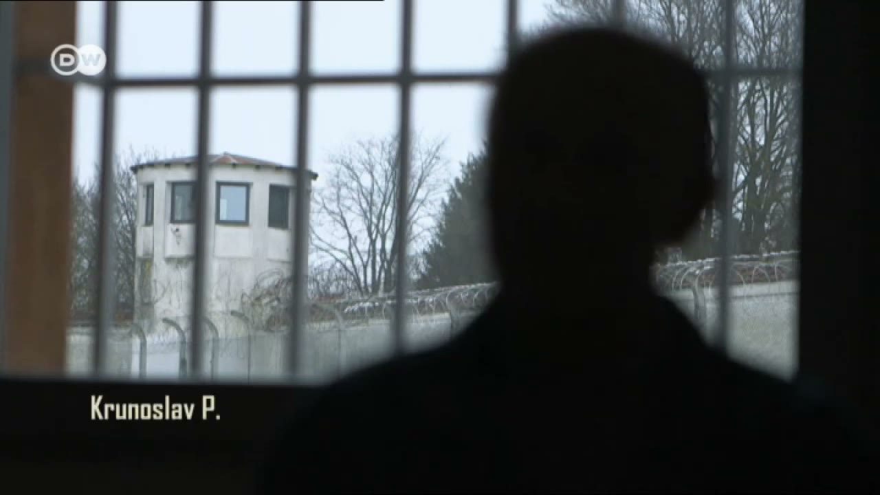 A man in silhouette at a barred prison window looking out at a watchtower and a razor wire wall, the caption Krunoslav P. in the lower left corner