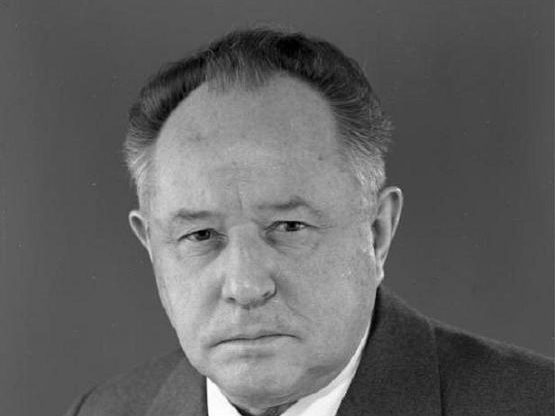 A black and white portrait of Erich Mielke in a suit and patterned tie