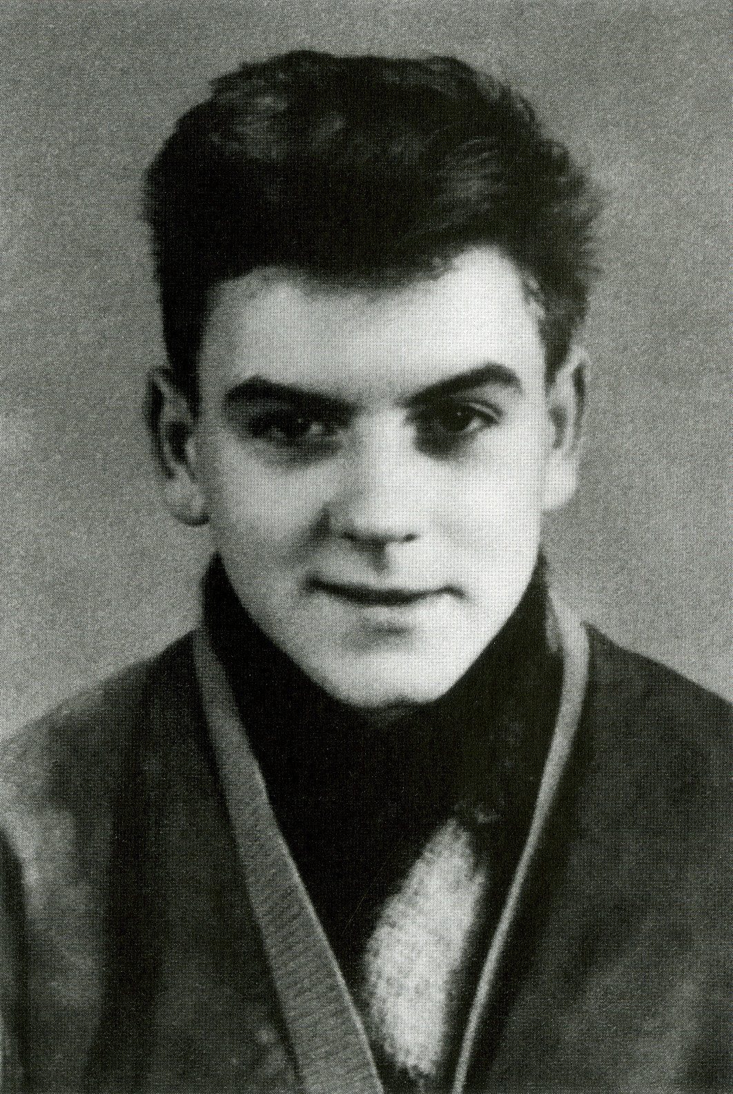 A black and white portrait of Michael Gartenschläger as a teenager, with dark swept-back hair, a scarf and a jacket