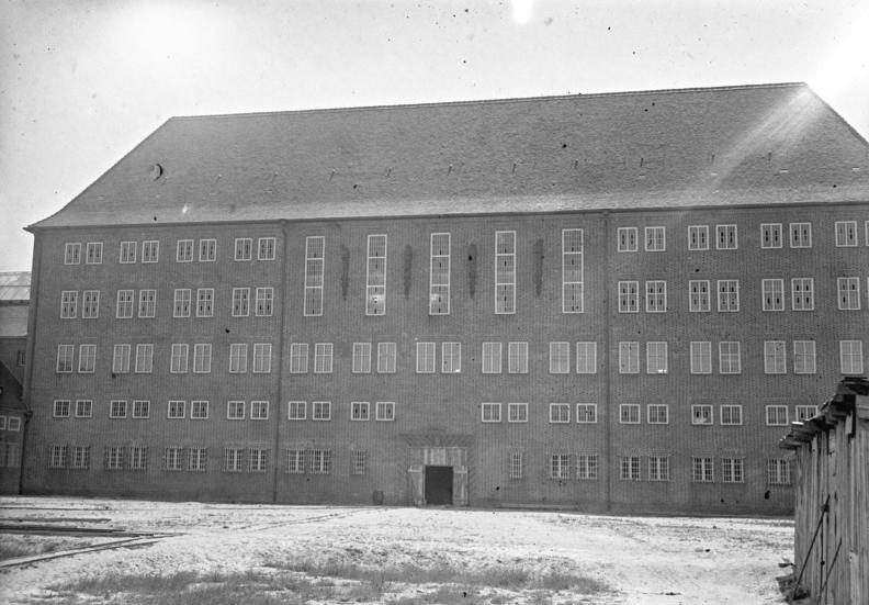A long four-storey prison block with rows of barred windows behind an open yard