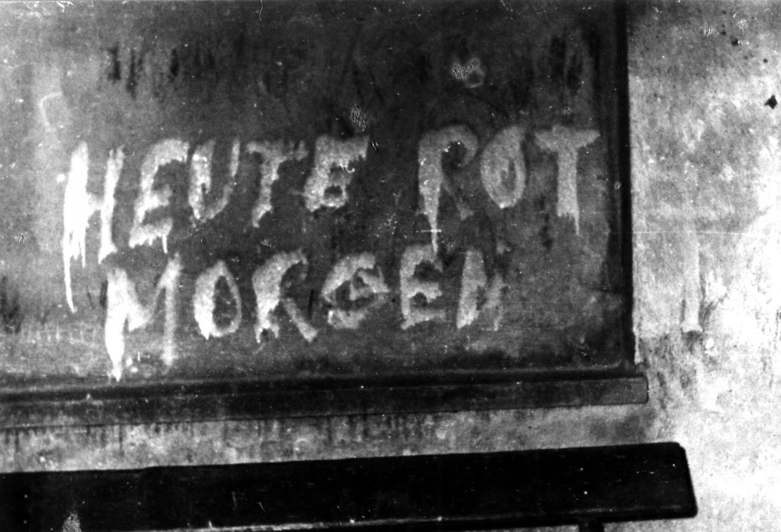 The words HEUTE ROT MORGEN painted in white on a dark wall; the last word of the slogan is outside the frame
