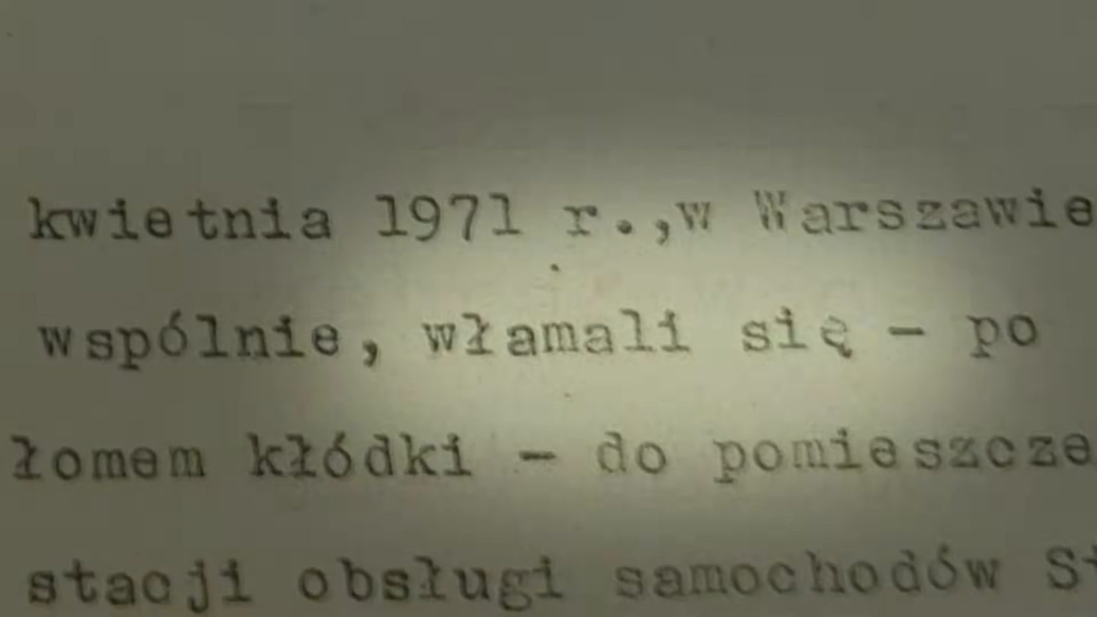 A close-up of typewritten lines: kwietnia 1971 r., w Warszawie wspólnie, włamali się, po zerwaniu łomem kłódki, do pomieszczenia stacji obsługi samochodów