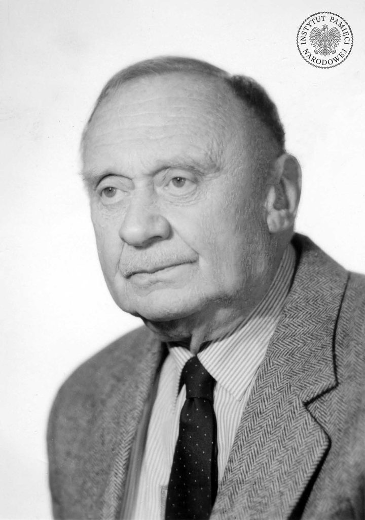 A black and white portrait of an older man in a tweed jacket and striped shirt; an archive stamp sits in the top right corner