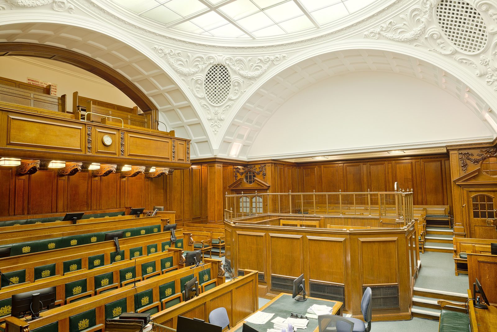 The interior of Court One at the Old Bailey seen from the bench, the panelled dock in the centre with rows of benches in front of it and a public gallery above