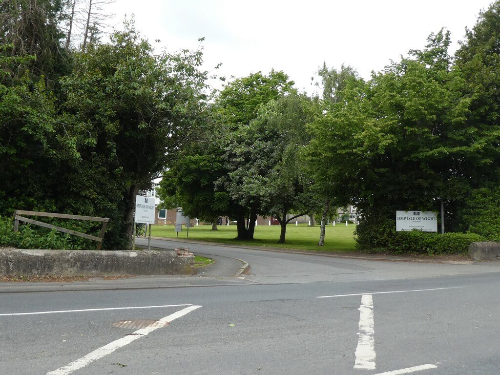 The gatehouse and entrance road of a Victorian prison, a long brick wall running away to the right under a grey sky
