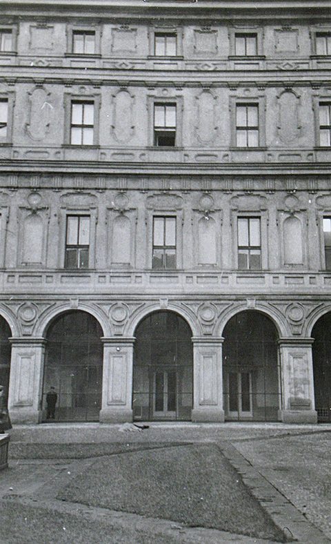 The courtyard facade of the Czernin Palace on 10 March 1948: an arcade at ground level, three rows of windows above it, one casement in the second row from the top standing open, and a small bundle on the paving at the foot of the arcade, where the body lay