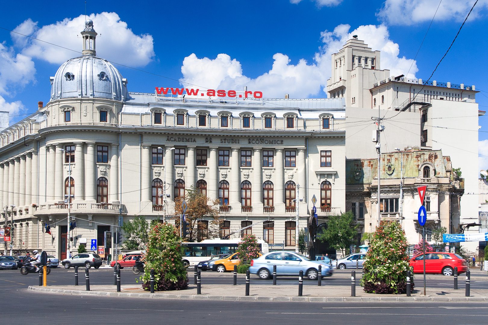 The domed neoclassical building of the Academy of Economic Studies on Piata Romana in Bucharest, its name carved along the facade, traffic crossing in front