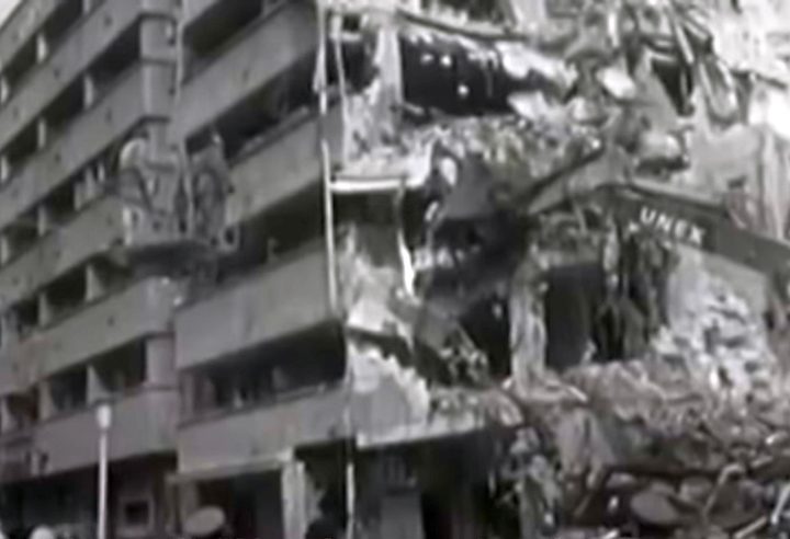 A city block in central Bucharest torn open by the 1977 earthquake: the balconies of the surviving half standing over a mound of rubble where the rest of the building came down into the street