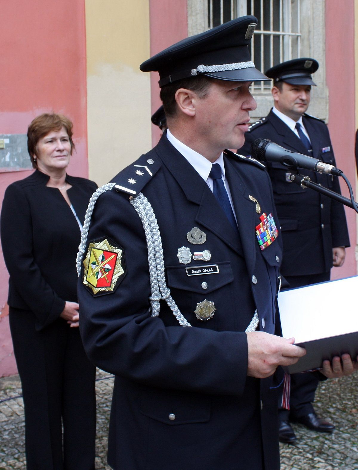 Radek Galaš in police dress uniform speaking at a microphone, his name tag reading Radek GALAŠ