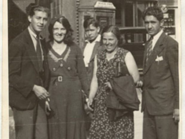 Five people standing together on a Prague street in front of a shop window, photographed by a street photographer in 1933
