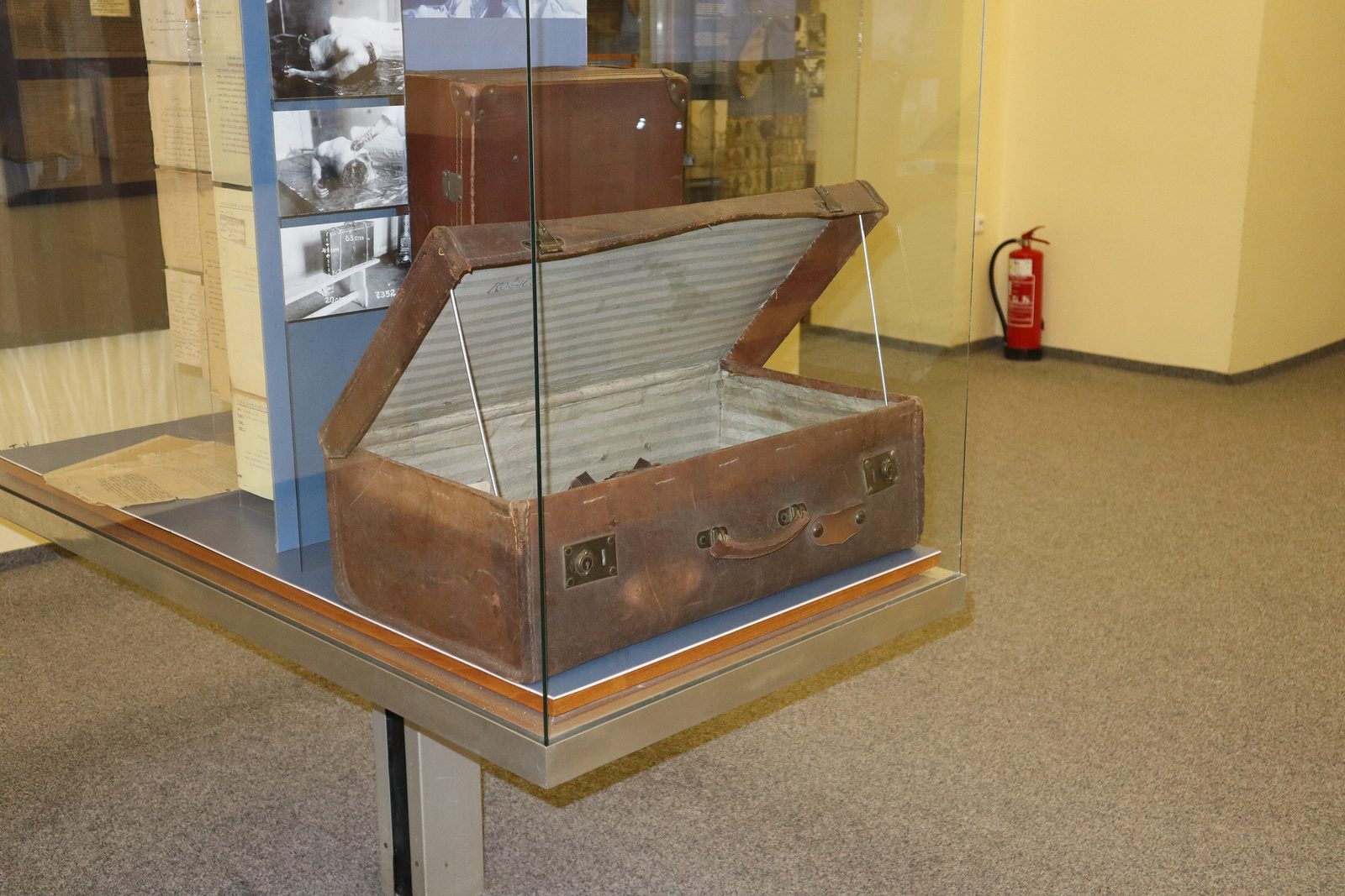 One of the suitcases from the case, open in a glass display cabinet at the Police Museum in Prague, with a second case standing behind it