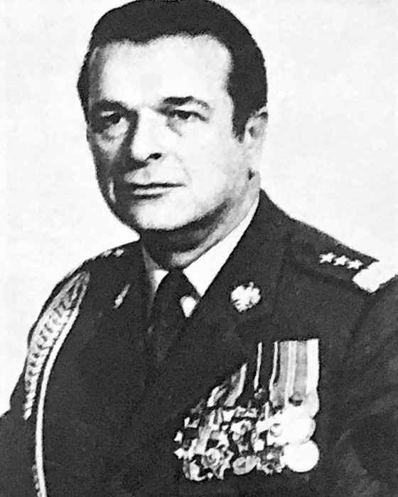 A black and white official portrait of a man in a dark dress uniform with braid, stars on the shoulder boards and rows of medals