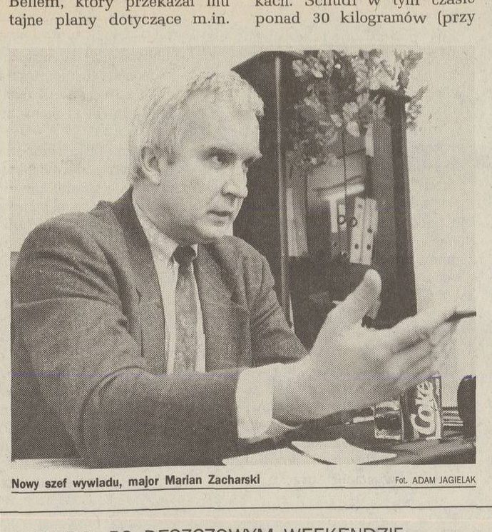 A newspaper photograph of Marian Zacharski at a desk, grey haired, in a jacket and tie, gesturing with one hand, a can of Coke on the desk, captioned Nowy szef wywiadu, major Marian Zacharski