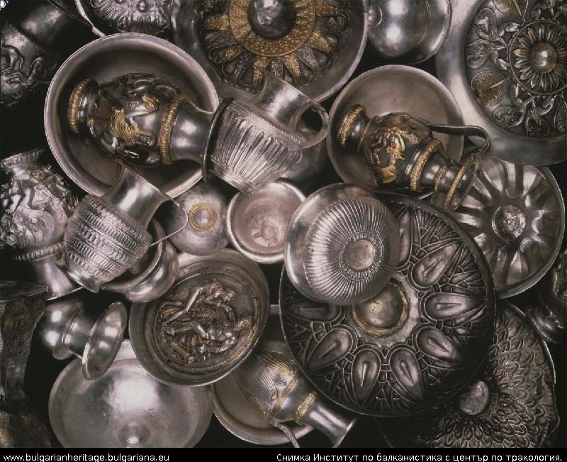 Dozens of gilded silver jugs, bowls and dishes laid together against a dark ground, several worked with figures and gilded ornament